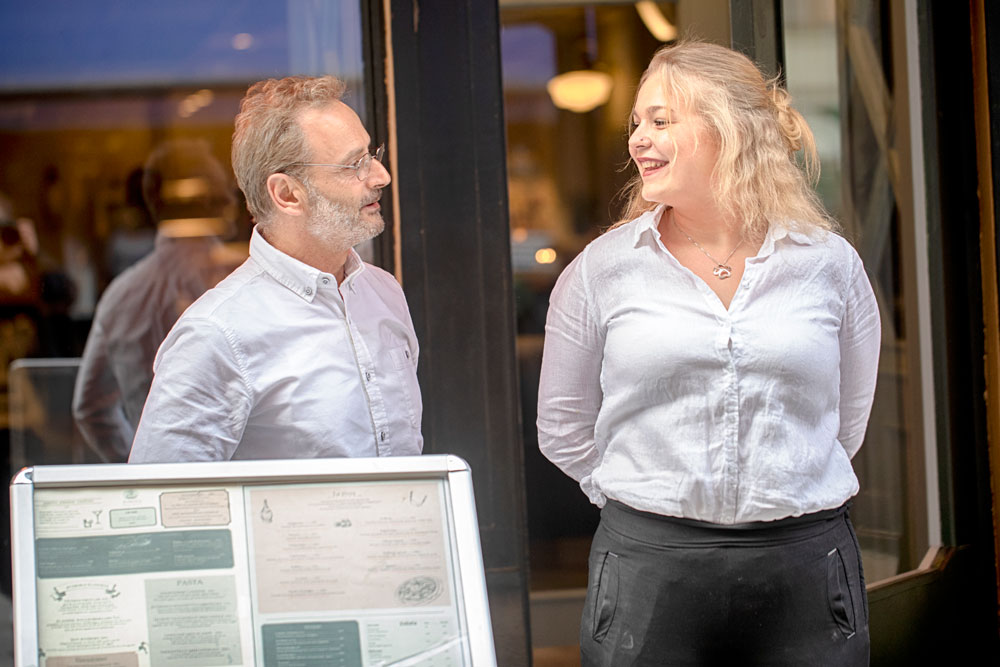 En man och en kvinna i vita skjortor ler mot varandra
